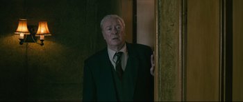 Movie still from “Harry Brown” (2009), directed by Daniel Barber – An older man wearing a suit and tie looking into a mirror; Medium shot, Low angle