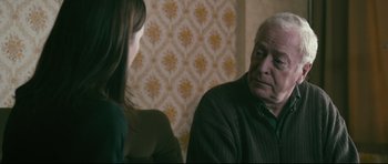 Movie still from “Harry Brown” (2009), directed by Daniel Barber – An older man and a young woman sitting at a table; Close Up shot, Over the shoulder angle