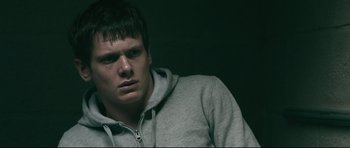 Movie still from “Harry Brown” (2009), directed by Daniel Barber – A young man in a gray hoodie is looking at the camera; Close Up shot, Low angle
