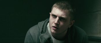 Movie still from “Harry Brown” (2009), directed by Daniel Barber – A man with a beard and a gray jacket is looking at the camera; Close Up shot, Over the shoulder angle