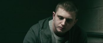 Movie still from “Harry Brown” (2009), directed by Daniel Barber – A young man is sitting in a dark room; Close Up shot, High angle