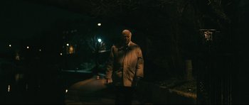 Movie still from “Harry Brown” (2009), directed by Daniel Barber – An older man standing in the dark at night; Medium shot, Low angle