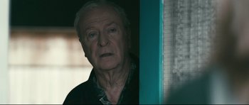 Movie still from “Harry Brown” (2009), directed by Daniel Barber – An older man standing in front of a window; Close Up shot, Over the shoulder angle