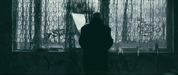 Movie still from “Harry Brown” (2009), directed by Daniel Barber – An older man sitting in front of a window; Medium shot, Low angle
