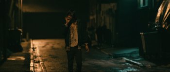 Movie still from “Harry Brown” (2009), directed by Daniel Barber – A person standing in the dark talking on a cell phone; Medium shot, Low angle