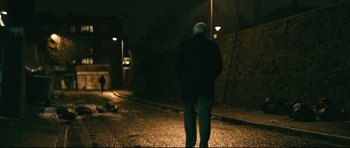 Movie still from “Harry Brown” (2009), directed by Daniel Barber – An older man walking down a street at night; Wide shot, Low angle