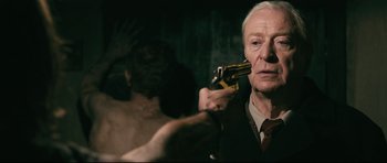 Movie still from “Harry Brown” (2009), directed by Daniel Barber – An older man is holding a knife in front of a mirror; Close Up shot, Over the shoulder angle