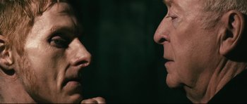 Movie still from “Harry Brown” (2009), directed by Daniel Barber – A man and a woman face to face in front of a dark background; Close Up shot, Over the shoulder angle