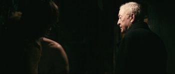 Movie still from “Harry Brown” (2009), directed by Daniel Barber – A man and a woman standing next to each other in the dark; Medium shot, Over the shoulder angle
