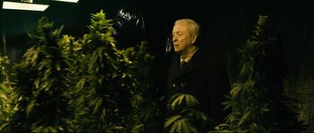 Movie still from “Harry Brown” (2009), directed by Daniel Barber – An older man standing next to a plant; Medium shot, Low angle