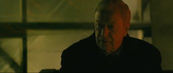 Movie still from “Harry Brown” (2009), directed by Daniel Barber – An older man in a black jacket looking at the camera; Close Up shot, High angle