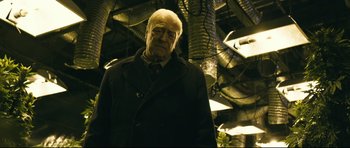 Movie still from “Harry Brown” (2009), directed by Daniel Barber – An older man wearing a black coat and a neck tie; Medium shot, Low angle