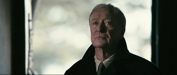 Movie still from “Harry Brown” (2009), directed by Daniel Barber – An older man wearing a black coat and a white shirt; Close Up shot, Low angle