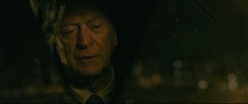 Movie still from “Harry Brown” (2009), directed by Daniel Barber – An older man wearing a black hat and a suit; Close Up shot, Over the shoulder angle