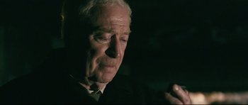 Movie still from “Harry Brown” (2009), directed by Daniel Barber – An older man in a suit and tie looking down; Close Up shot, Over the shoulder angle