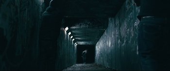 Movie still from “Harry Brown” (2009), directed by Daniel Barber – A person standing in a dark tunnel with lights on; Wide shot, Low angle