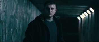 Movie still from “Harry Brown” (2009), directed by Daniel Barber – A man in a black jacket standing next to a wall; Medium shot, Low angle