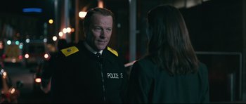 Movie still from “Harry Brown” (2009), directed by Daniel Barber – A man in a police uniform talking to a woman; Medium shot, Over the shoulder angle
