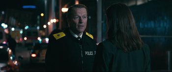 Movie still from “Harry Brown” (2009), directed by Daniel Barber – A man in a police uniform talking to a woman; Medium shot, Over the shoulder angle