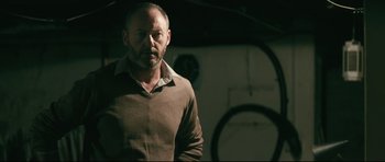 Movie still from “Harry Brown” (2009), directed by Daniel Barber – A man in a brown shirt is standing in a room; Medium shot, Low angle