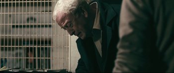 Movie still from “Harry Brown” (2009), directed by Daniel Barber – An older man in a suit and tie looking down; Close Up shot, Over the shoulder angle