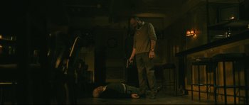 Movie still from “Harry Brown” (2009), directed by Daniel Barber – A man standing next to another man in a dark room; Wide shot, Low angle