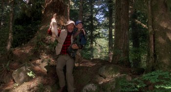 Movie still from “Harry and the Hendersons” (1987), directed by William Dear – A man and a woman posing for a picture in the woods; Wide shot, Low angle