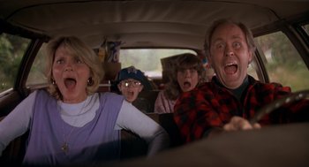 Movie still from “Harry and the Hendersons” (1987), directed by William Dear – A group of people riding in the back of a car; Medium shot, Low angle