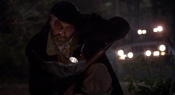 Movie still from “Harry and the Hendersons” (1987), directed by William Dear – A man with a beard and a hat is holding a flashlight; Medium shot, Low angle