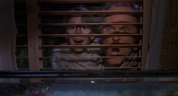 Movie still from “Harry and the Hendersons” (1987), directed by William Dear – A man and a child looking through a window; Medium shot, Low angle