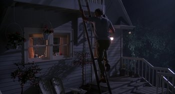 Movie still from “Harry and the Hendersons” (1987), directed by William Dear – A man climbing up a ladder on a porch at night; Wide shot, Low angle