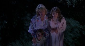 Movie still from “Harry and the Hendersons” (1987), directed by William Dear – A woman and two girls in nightgowns posing for a picture; Medium shot, High angle