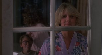 Movie still from “Harry and the Hendersons” (1987), directed by William Dear – A woman looking out of a window at a child; Medium shot, Over the shoulder angle