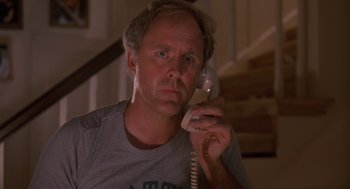 Movie still from “Harry and the Hendersons” (1987), directed by William Dear – A man holding a phone up to his ear; Close Up shot, Low angle