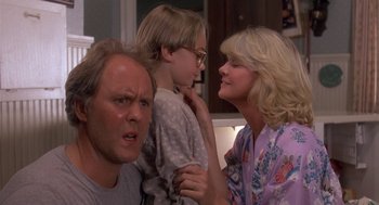 Movie still from “Harry and the Hendersons” (1987), directed by William Dear – A man and a woman and a child in a room; Medium shot, Over the shoulder angle