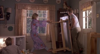 Movie still from “Harry and the Hendersons” (1987), directed by William Dear – A woman in a kimono is pushing a wooden object; Wide shot, Low angle