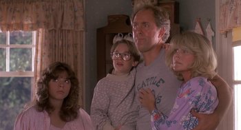 Movie still from “Harry and the Hendersons” (1987), directed by William Dear – A man and two women and a girl are standing in a living room; Medium shot, Low angle