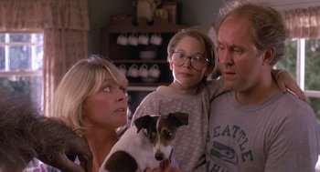 Movie still from “Harry and the Hendersons” (1987), directed by William Dear – A woman and two men and a small dog in a living room; Close Up shot, Low angle