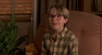 Movie still from “Harry and the Hendersons” (1987), directed by William Dear – A young boy wearing glasses sitting in a chair; Close Up shot, High angle