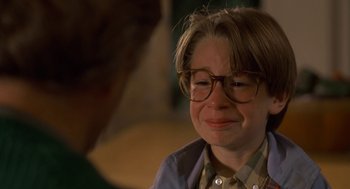 Movie still from “Harry and the Hendersons” (1987), directed by William Dear – A woman with glasses crying while sitting in a chair; Close Up shot, High angle