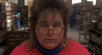 Movie still from “Harry and the Hendersons” (1987), directed by William Dear – A woman with a big hair wig and glasses; Close Up shot, Over the shoulder angle