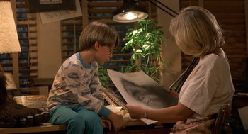 Movie still from “Harry and the Hendersons” (1987), directed by William Dear – A young boy is looking at an image with an older woman; Medium shot, Over the shoulder angle