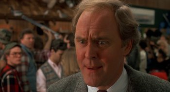 Movie still from “Harry and the Hendersons” (1987), directed by William Dear – An older man in a suit and tie looking at the camera; Close Up shot, Over the shoulder angle