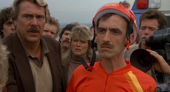 Movie still from “Harry and the Hendersons” (1987), directed by William Dear – A group of people standing in a line with one man wearing a helmet; Close Up shot, Low angle