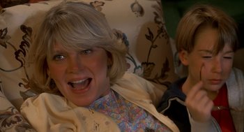 Movie still from “Harry and the Hendersons” (1987), directed by William Dear – An older woman and a young boy sitting on a couch; Close Up shot, High angle