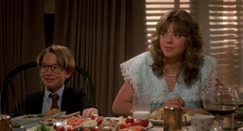 Movie still from “Harry and the Hendersons” (1987), directed by William Dear – A woman sitting at a table with a man; Medium shot, Over the shoulder angle