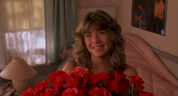 A woman sitting in front of a bouquet of red flowers