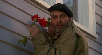Movie still from “Harry and the Hendersons” (1987), directed by William Dear – A man holding a red flower while wearing a hat; Close Up shot, Low angle