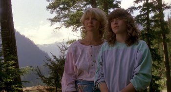 Movie still from “Harry and the Hendersons” (1987), directed by William Dear – A woman standing next to a young girl in front of a tree; Medium shot, Low angle