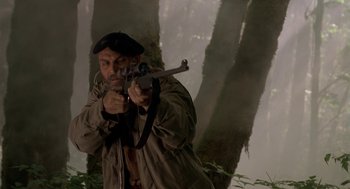Movie still from “Harry and the Hendersons” (1987), directed by William Dear – A man is holding a gun in the woods; Medium shot, Low angle